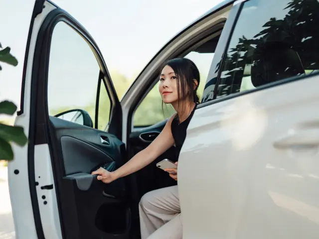 Young woman exiting the driver’s seat of a white minivan.