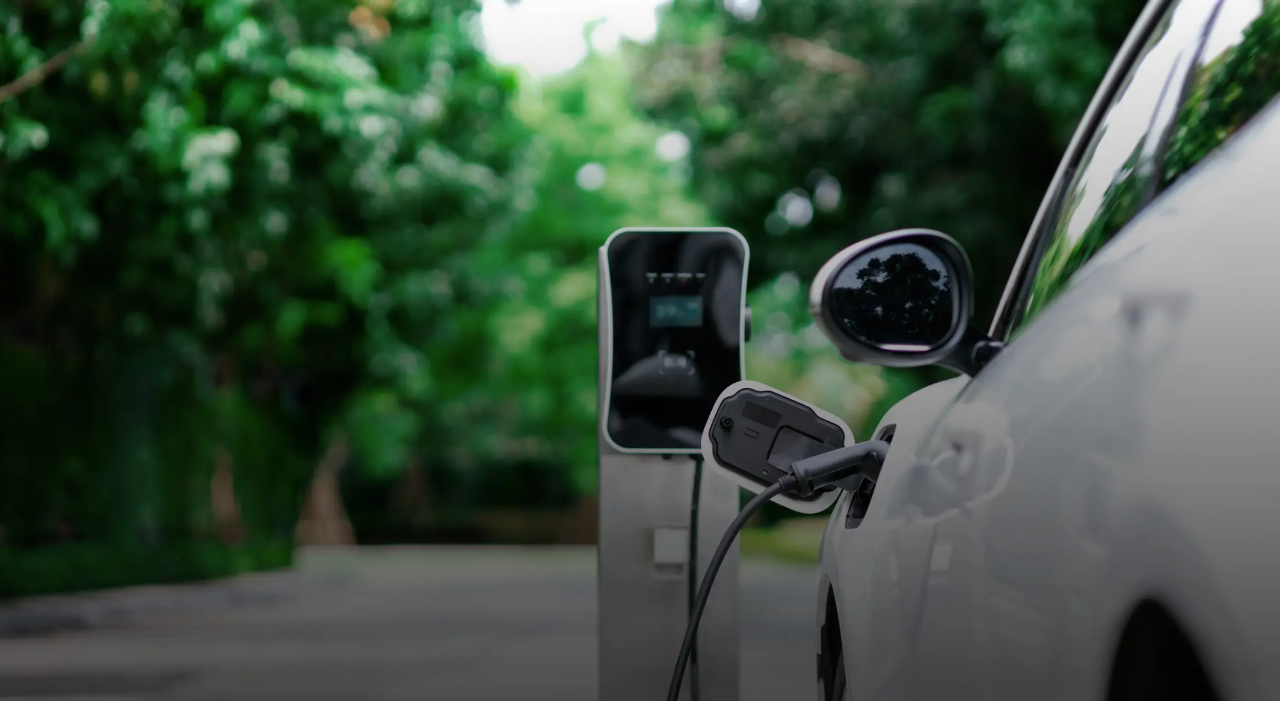 Un véhicule électrique blanc branché à une borne de recharge.